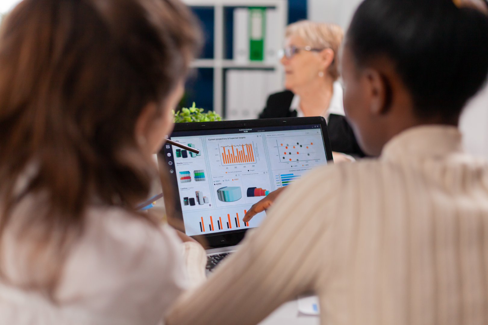 Two women in an office looking at reporting data on a laptop screen