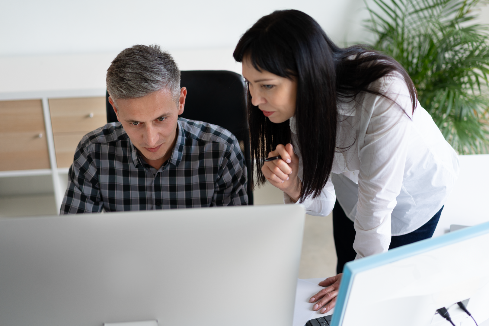 Two people looking at a computer screen in an office setting